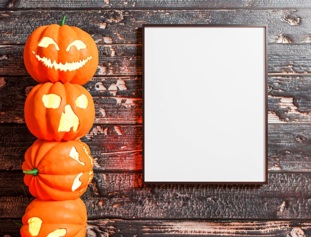 the canvas is on a wooden table. Next to the canvas are four pumpkins on top of each other.