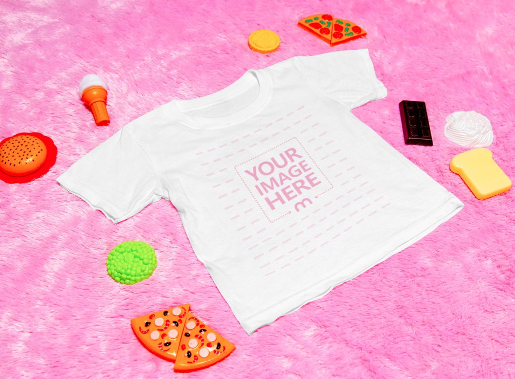 a t-shirt on a pink background. surrounded by toys